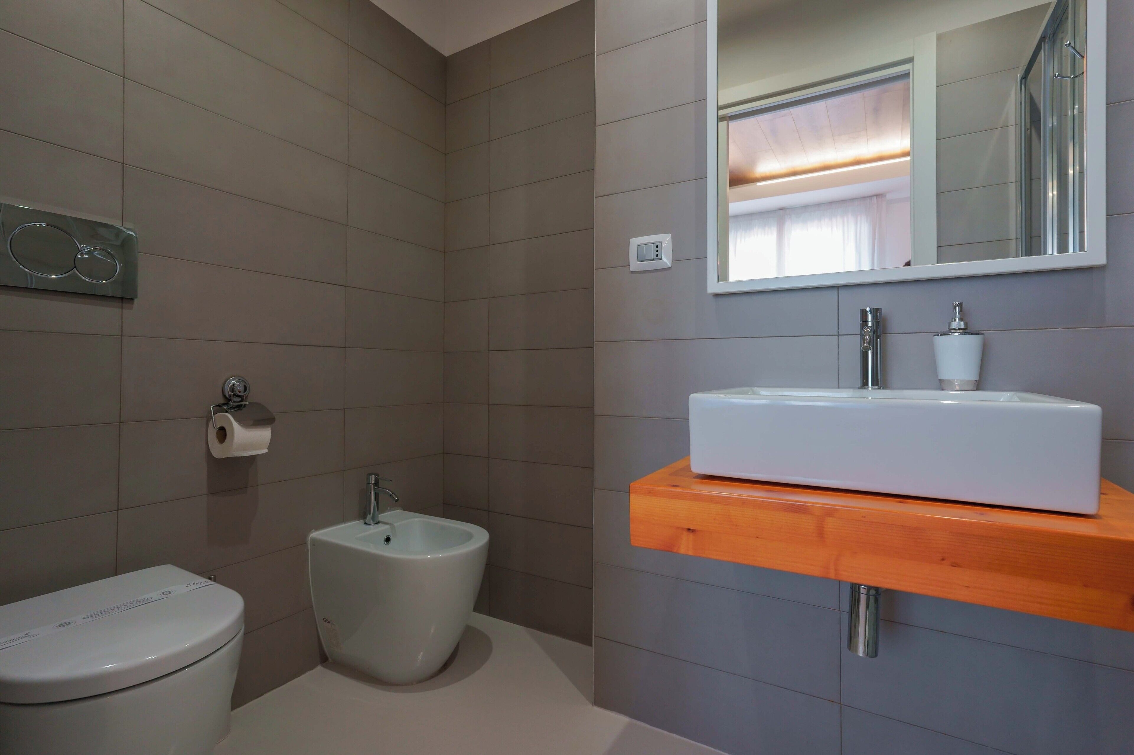 Une salle de bain moderne équipée de toilettes, d’un bidet et d’un lavabo, le tout installé sur un plan de toilette en bois.