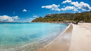 A beach with clear turquoise water, a sandy shore, and a mountainous backdrop. - Lumiere Rooms - Eja Sardinia (Cagliari)