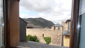 Blick aus einem Fenster auf ein Steingebäude mit einem Berg im Hintergrund.