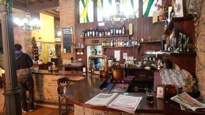Eine Bar mit einer Holztresen, Regalen mit Flaschen und einer Speisekarte auf dem Tresen.