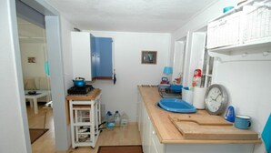A compact kitchen with a wooden countertop, a blue kettle, and a clock.