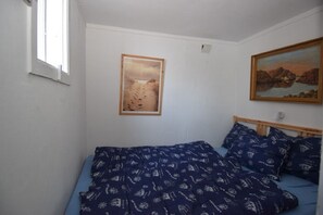 A bedroom with a bed, a window, and two framed pictures on the wall. - Solferie Holiday Cabin Ålefjærveien (Kristiansand)