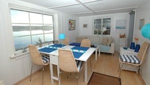 A dining area with a table set for four, surrounded by wicker chairs, a blue table runner, and a lamp.