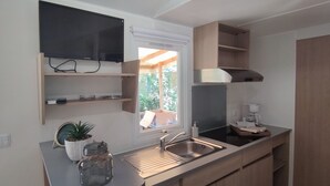 A modern kitchen with a built-in stove, a sink, and wooden cabinets. - Camping Du Pont D'Avignon (Avignon)
