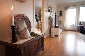 Una sala de estar con un aparador de madera, un jarrón blanco, una vela y una corona decorativa.