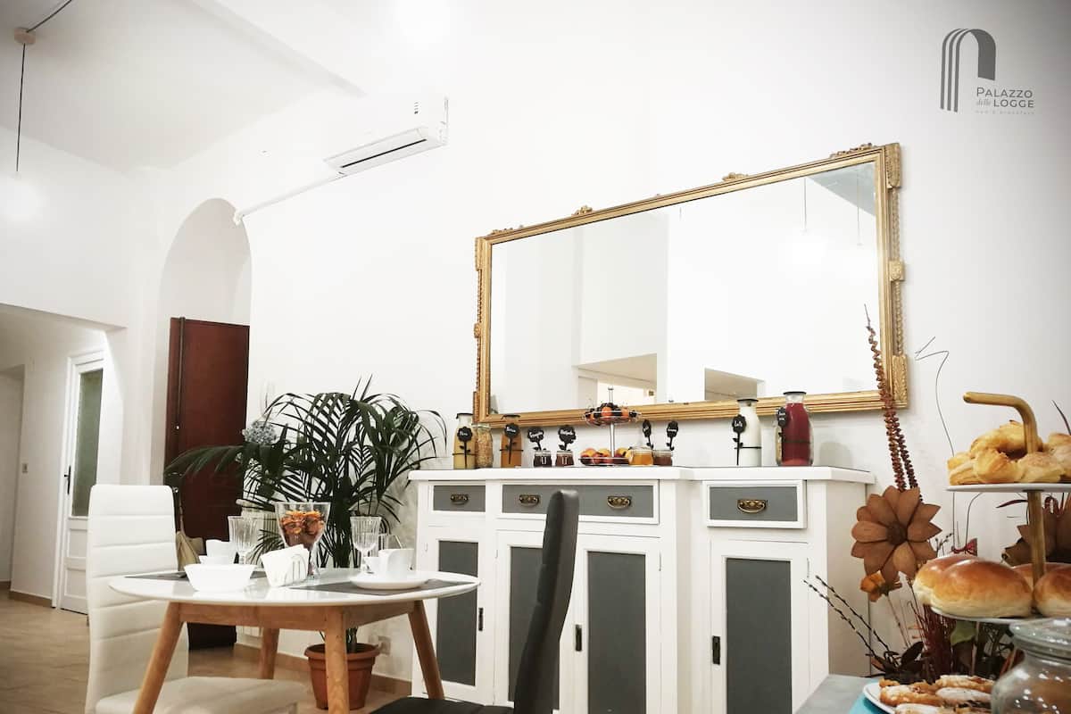 A dining area with a white table, chairs, a large mirror, and a cabinet with decorative items.