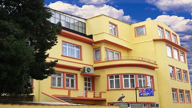 A yellow building with multiple windows and a balcony. - Yellow Rose Pansiyon (Çanakkale)