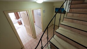 A staircase with a handrail, leading to a room with a door and a light fixture on the ceiling. - Yellow Rose Pansiyon (Çanakkale)