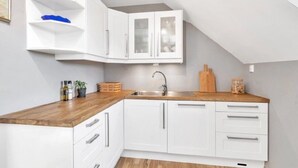 Eine moderne Küche mit weißen Schränken, einer Holz Arbeitsplatte und einer eingebauten Spüle.