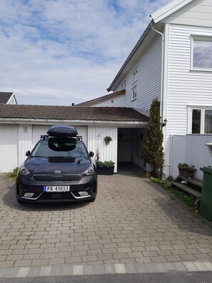 Um carro preto estacionado em frente a uma casa branca com telhado de telhas.