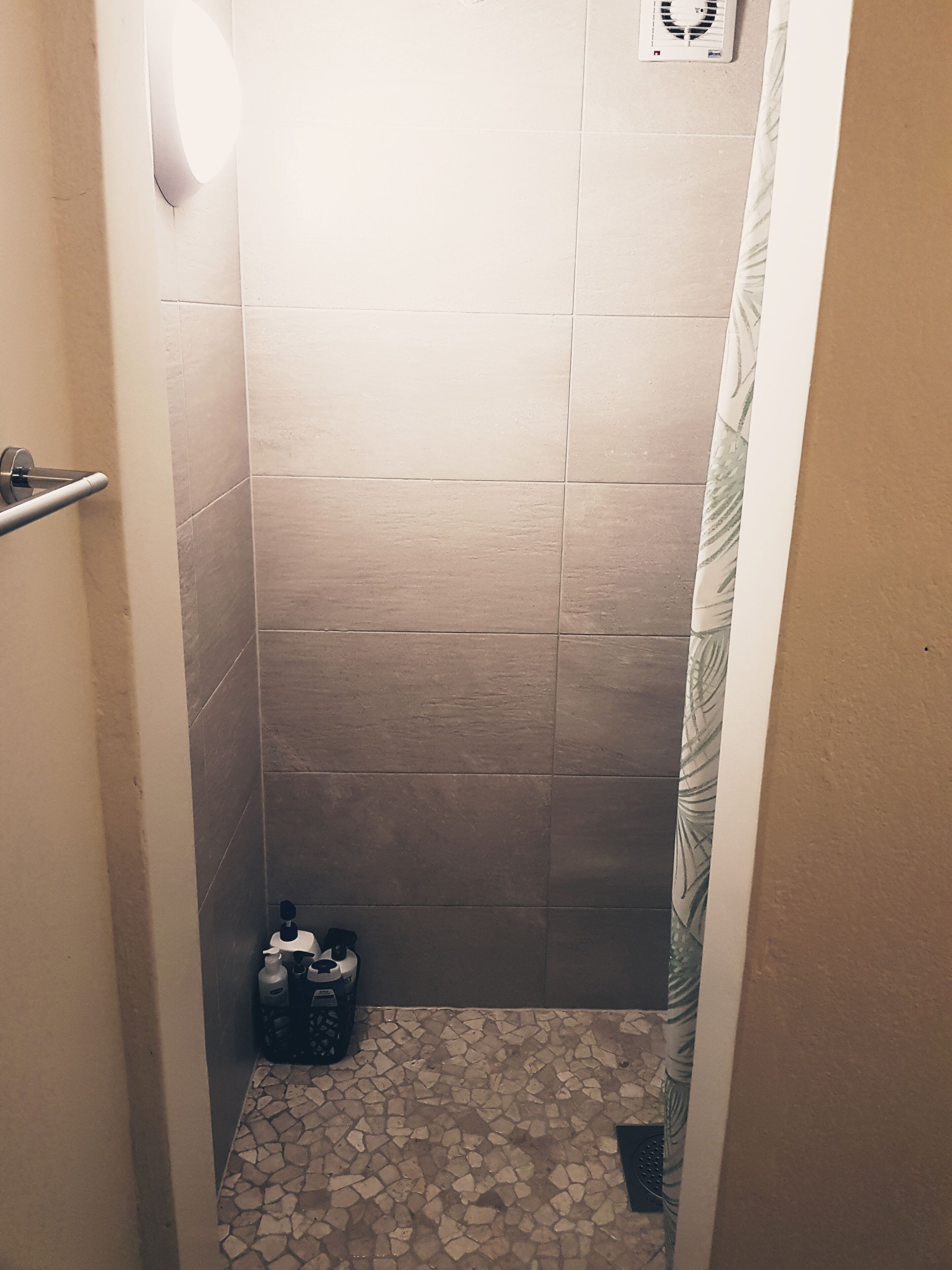 A small, tiled shower area with a tiled floor and a shower curtain.