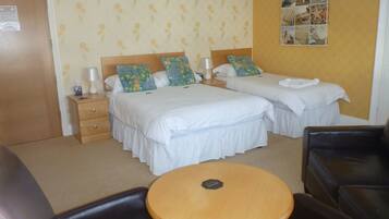 A hotel room with two beds, a wooden nightstand, a round table, and a black leather chair.