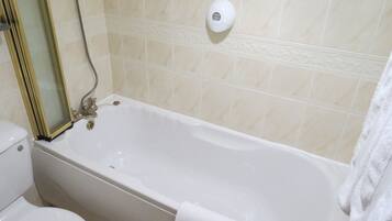 A bathroom with a bathtub, toilet, and a hand dryer.
