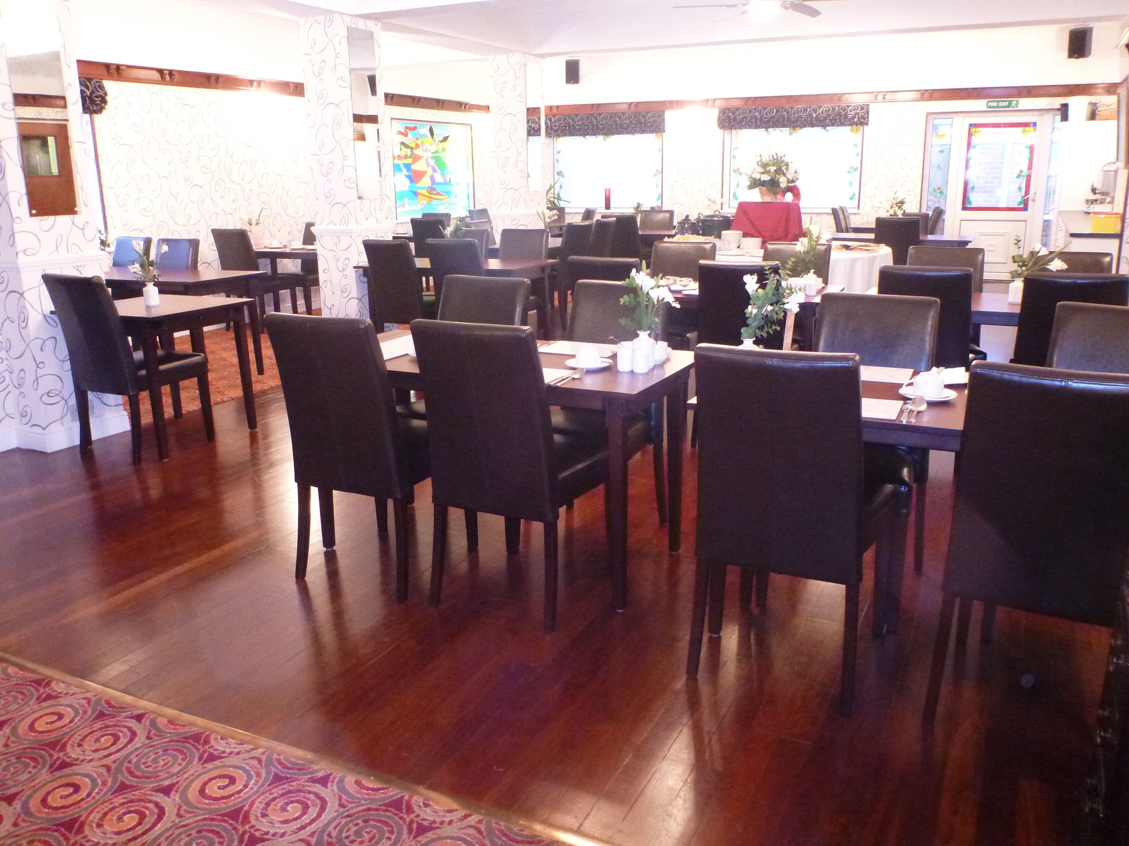 A dining area with multiple tables and chairs, a patterned carpet, and a decorative wall.