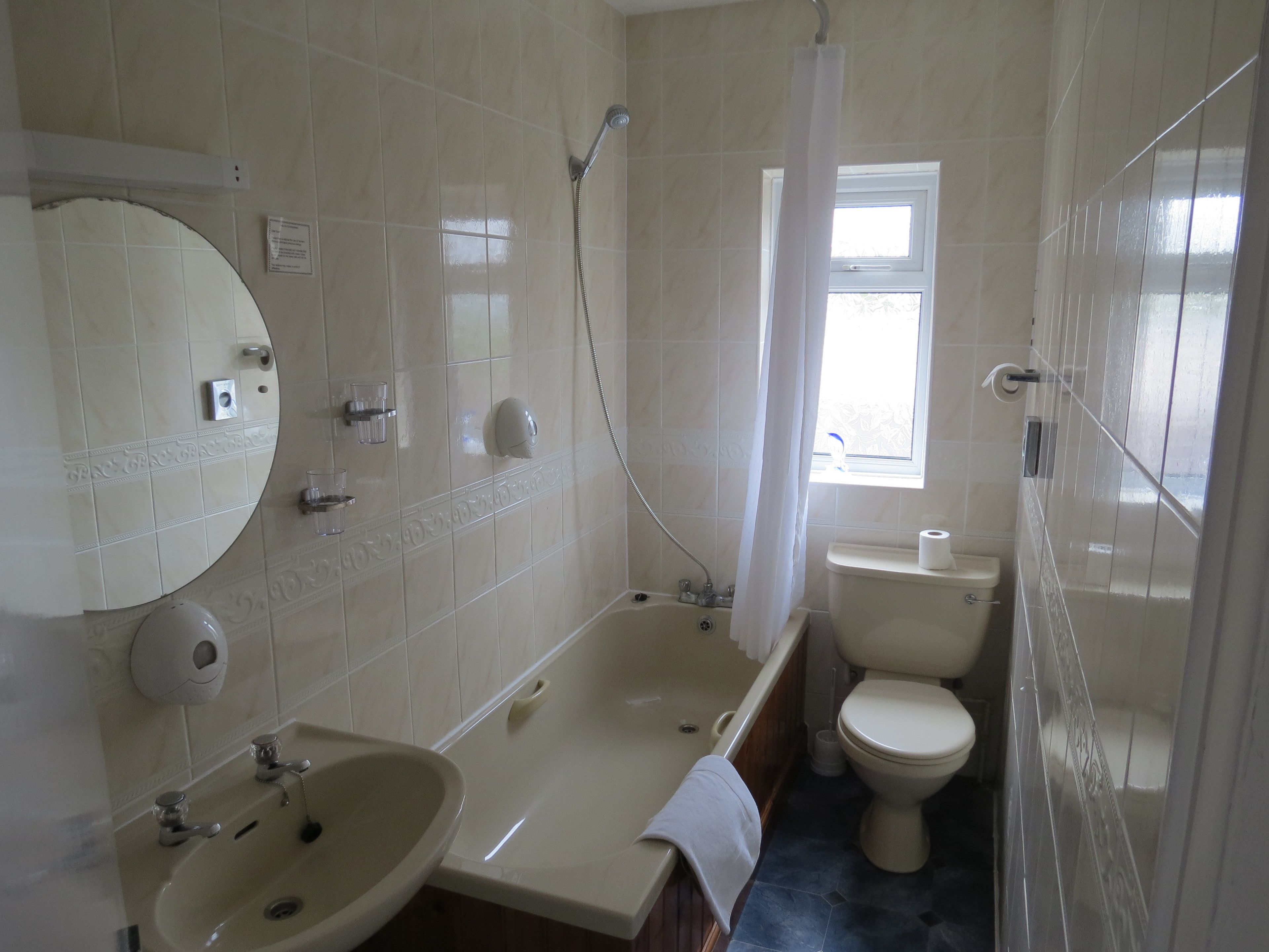Un baño con bañera, lavamanos, inodoro y ventana.