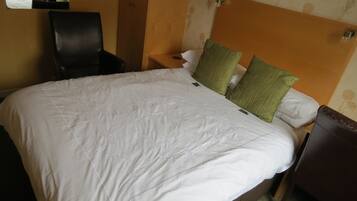 A hotel room with a large bed, a chair, a nightstand, and a mirror.