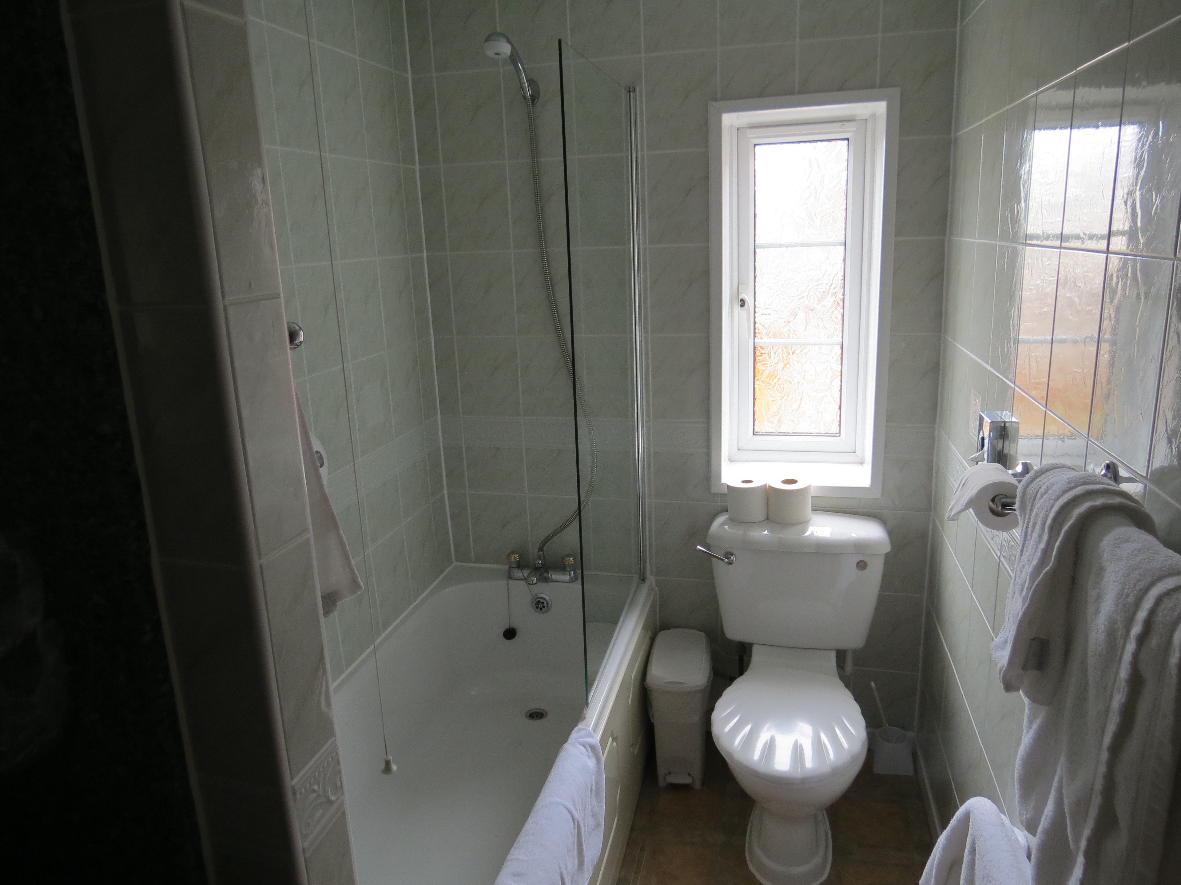 A bathroom with a bathtub, toilet, and a window.