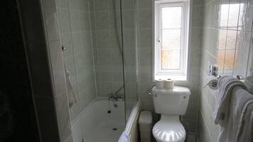 Un baño con bañera, inodoro y ventana.