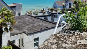 A coastal view with a clear sky, a beach, and a building with a balcony overlooking the sea. - Harbour View Guest House (St Ives)