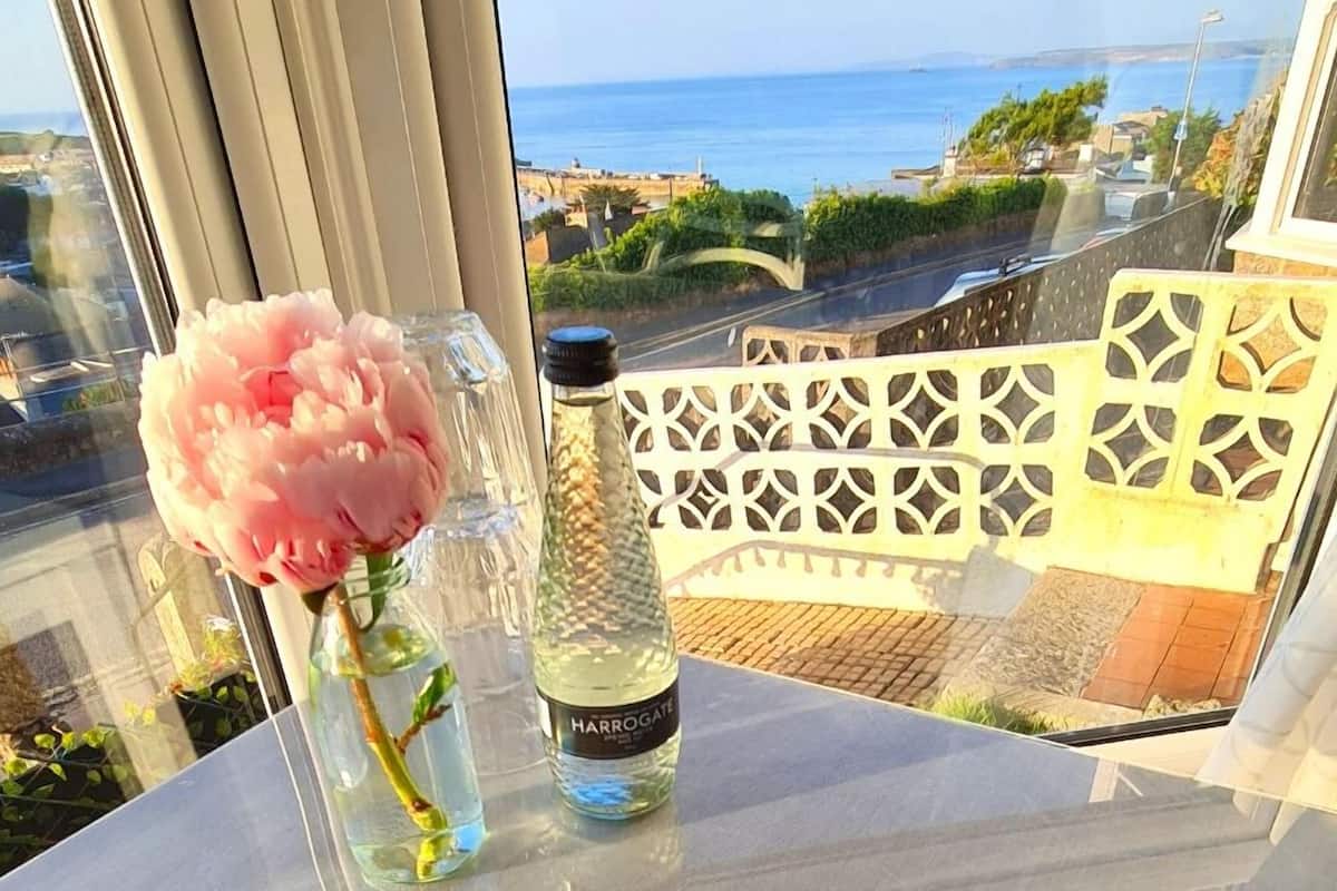 Ein Tisch mit einer Vase voller pinkfarbener Blumen und einer Flasche Harrogate Water.