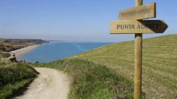 A wooden signpost with 'PUNTA ADERCI' and 'NATURA' visible.