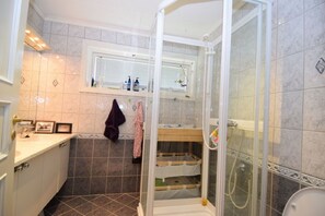 A bathroom with a glass shower enclosure, a sink with a mirror, and a towel rack. - Solferie Holiday Home Breimyråsen (Kristiansand)
