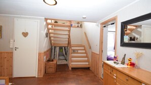A room with a wooden staircase leading to a lofted area, a white door with a heart decoration, and a mirror on the wall. - Solferie Holiday Home Breimyråsen (Kristiansand)