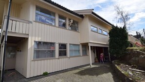A two-story building with a flat roof, a balcony on the second floor, and a paved driveway. - Solferie Holiday Home Breimyråsen (Kristiansand)