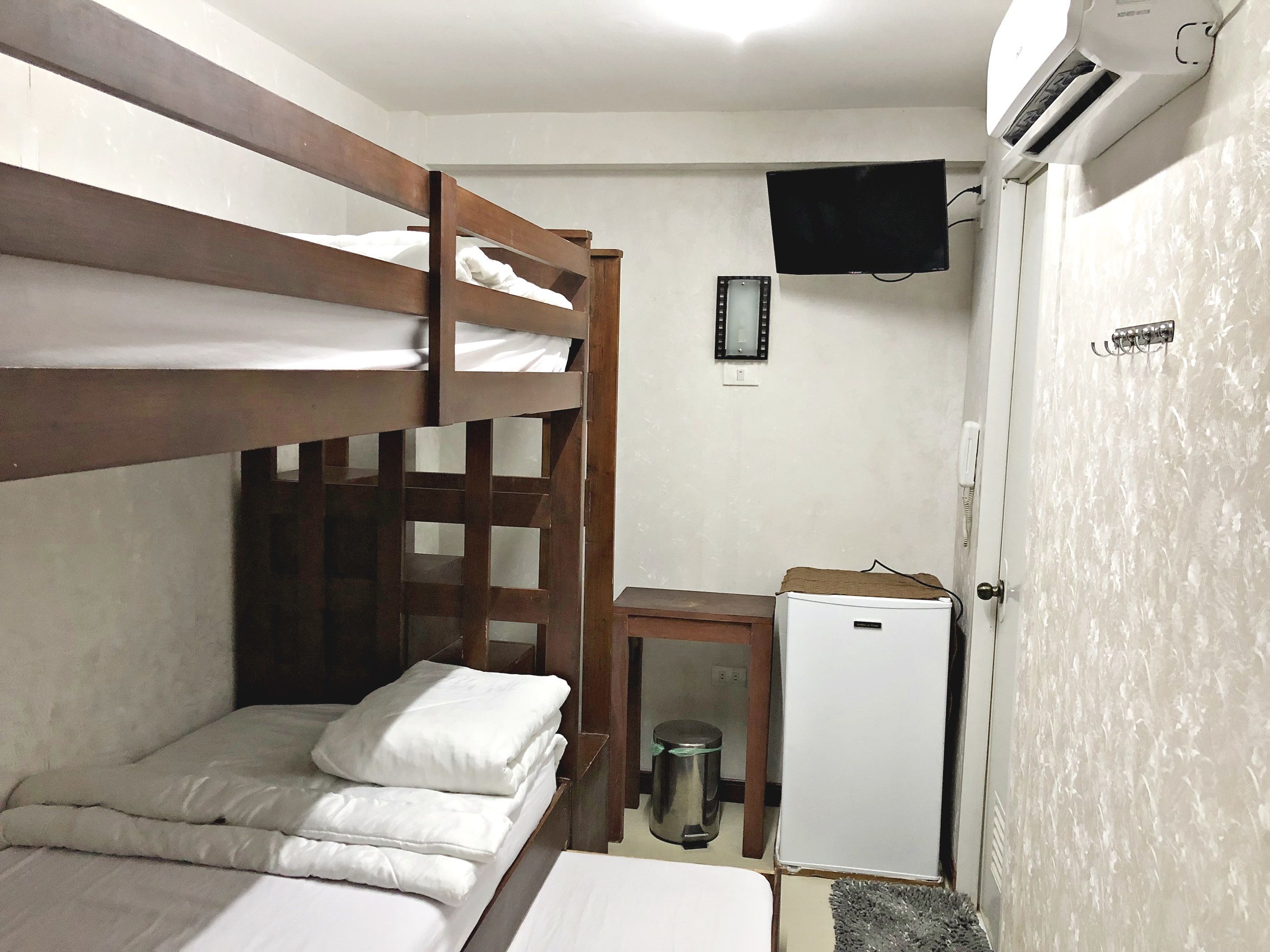 A bunk bed with a small desk and a refrigerator in a compact room.