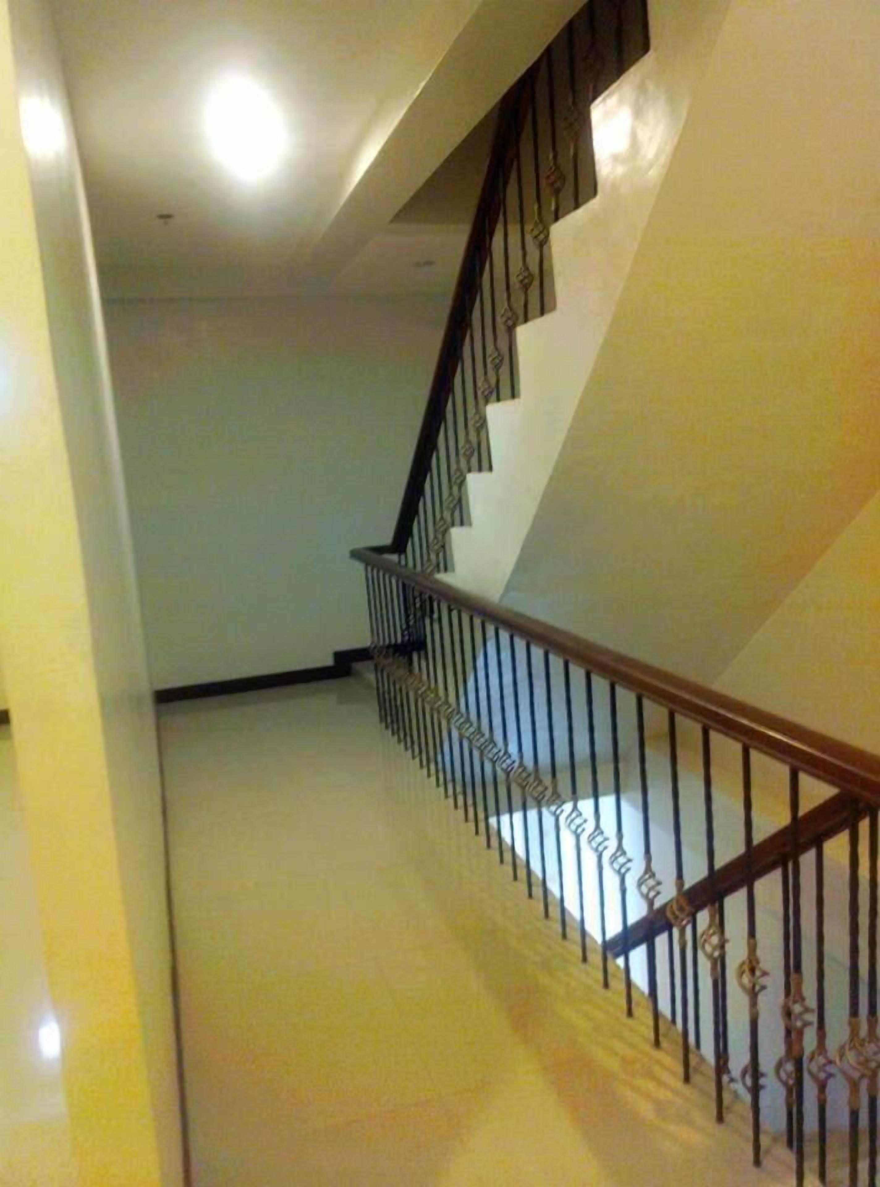 Una escalera con barandilla de madera y balaustradas de metal, que conduce a un piso superior.