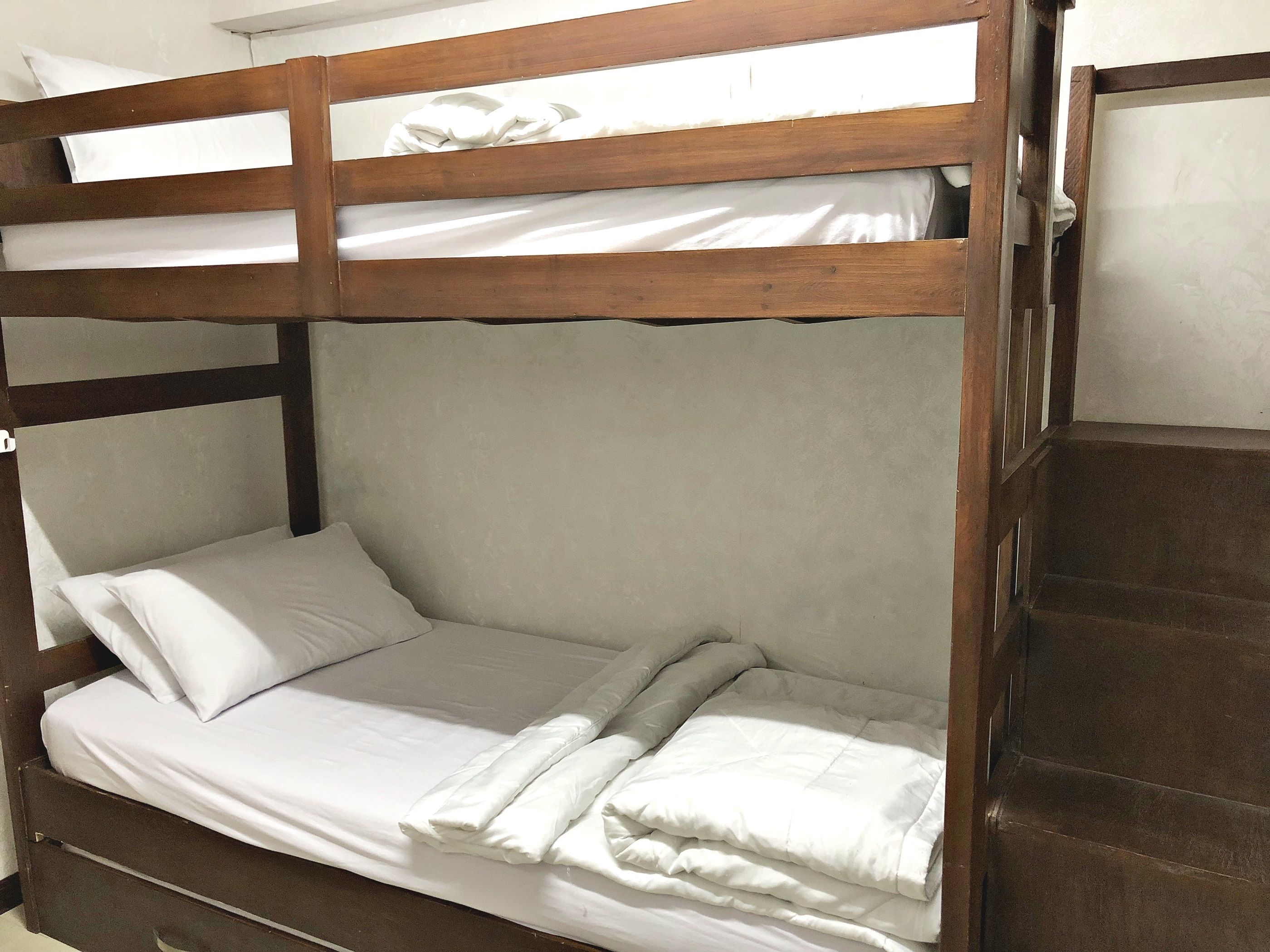 Una cama litera con ropa de cama blanca y cabecero de madera.