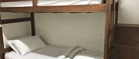 Una cama litera con ropa de cama blanca y cabecero de madera.