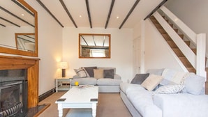 Ein Wohnzimmer mit Kamin, einer Couch, einem Couchtisch und einer Treppe.
