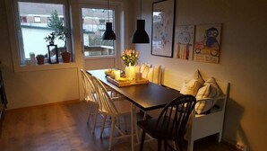 A dining area with a table and chairs, a vase with flowers, and artwork on the wall. - Solferie Holiday Apt. Johan Øydegards (Kristiansand)