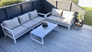 A wooden deck with a white sofa and a coffee table, surrounded by potted plants. - Solferie Holiday Apt. Johan Øydegards (Kristiansand)
