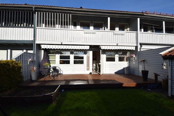 A two-story building with a covered patio, a small garden, and a single-story extension.
