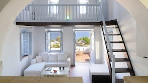 A spacious living area with a white sofa, a coffee table, and a balcony with a wooden railing. - Onar (Patmos)
