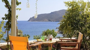 A wooden table with chairs and a view of the sea. - Onar (Patmos)