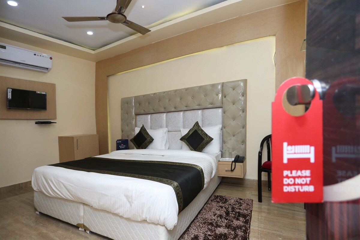 A hotel room with a bed, a television mounted on the wall, a ceiling fan, and a 'Please do not disturb' sign.