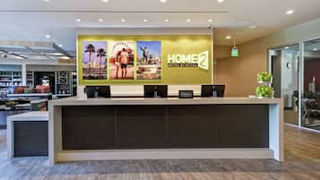 Een hotel receptiebalie met een groot bord waarop 'HOME2 Suites by Hilton' staat.