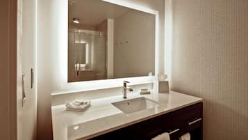 A modern bathroom with a large mirror, a sink, and a shower.