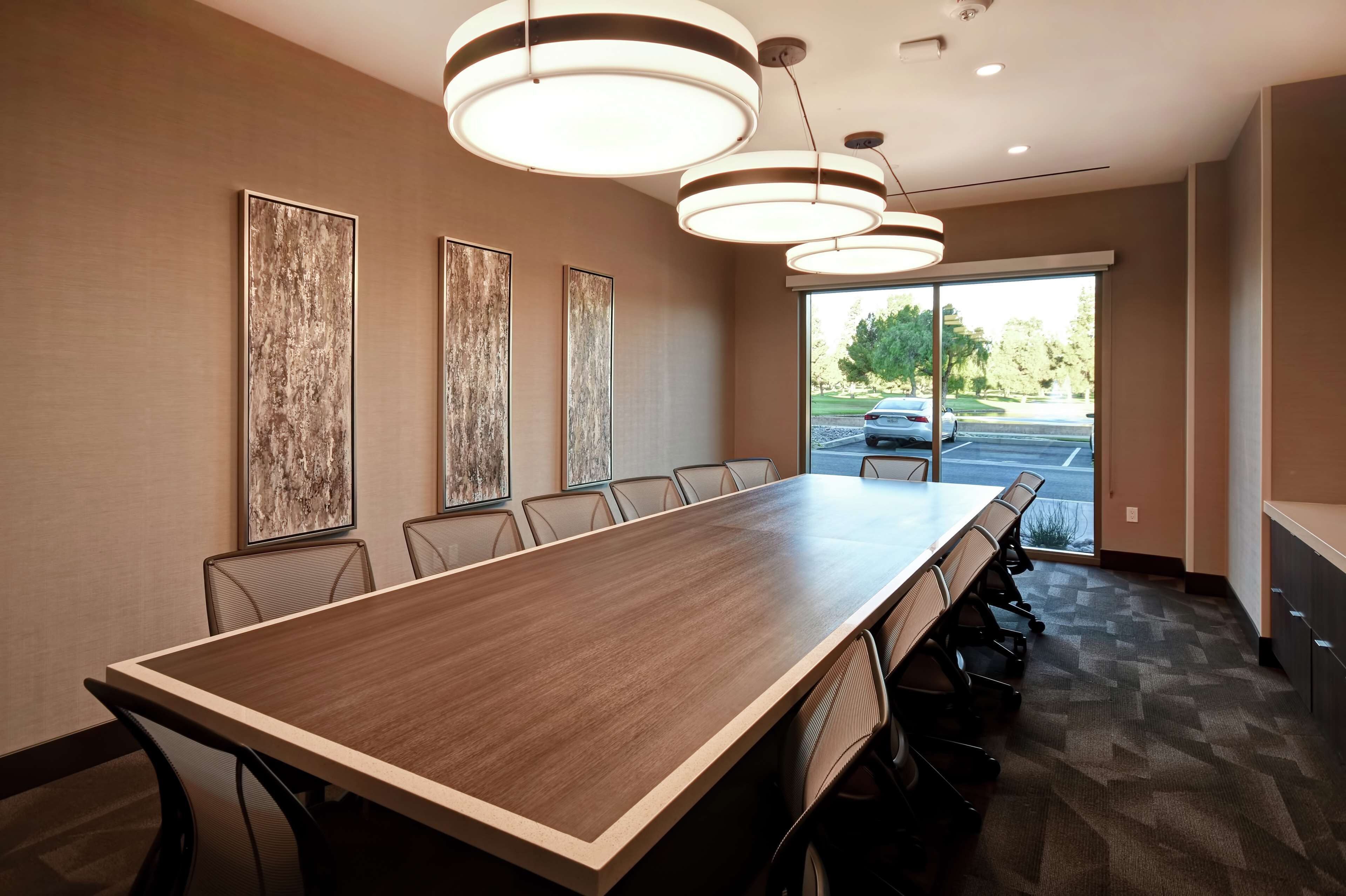 A conference room with a long table, chairs, and pendant lights.