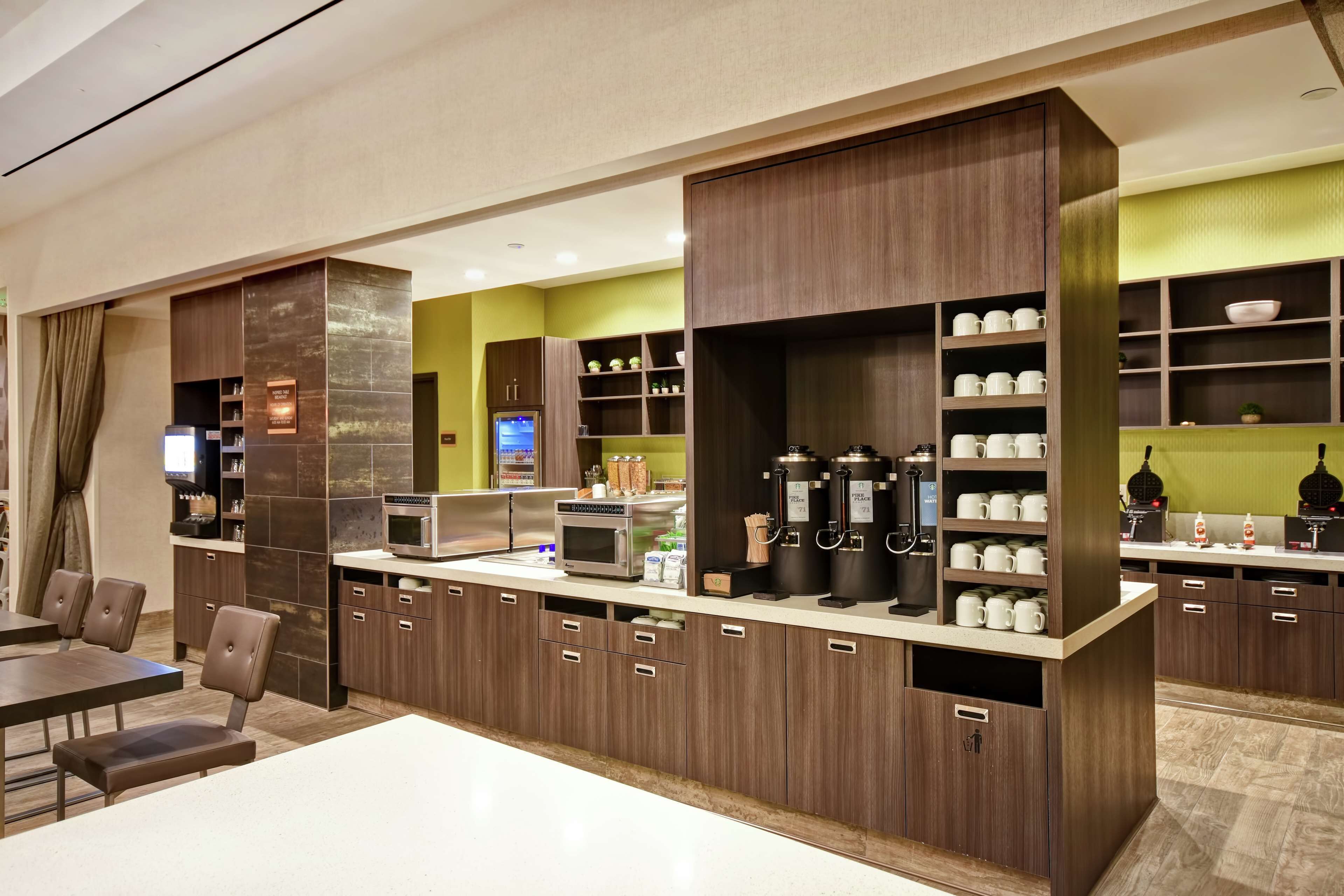 A modern kitchen with built-in appliances, wooden cabinets, and a coffee station.