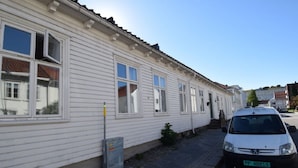 A white building with multiple windows and a parked car on the street. - Solferie Holiday Apt. Henrik Wergelands (Kristiansand)