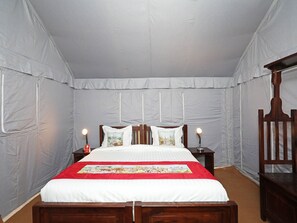 Un dormitorio con cama, mesitas de noche y una silla de madera.