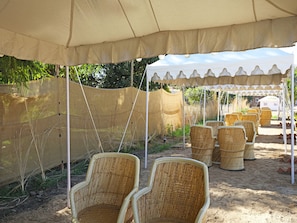 Un espacio de estar al aire libre con techo, sillas de mimbre y un toldo.