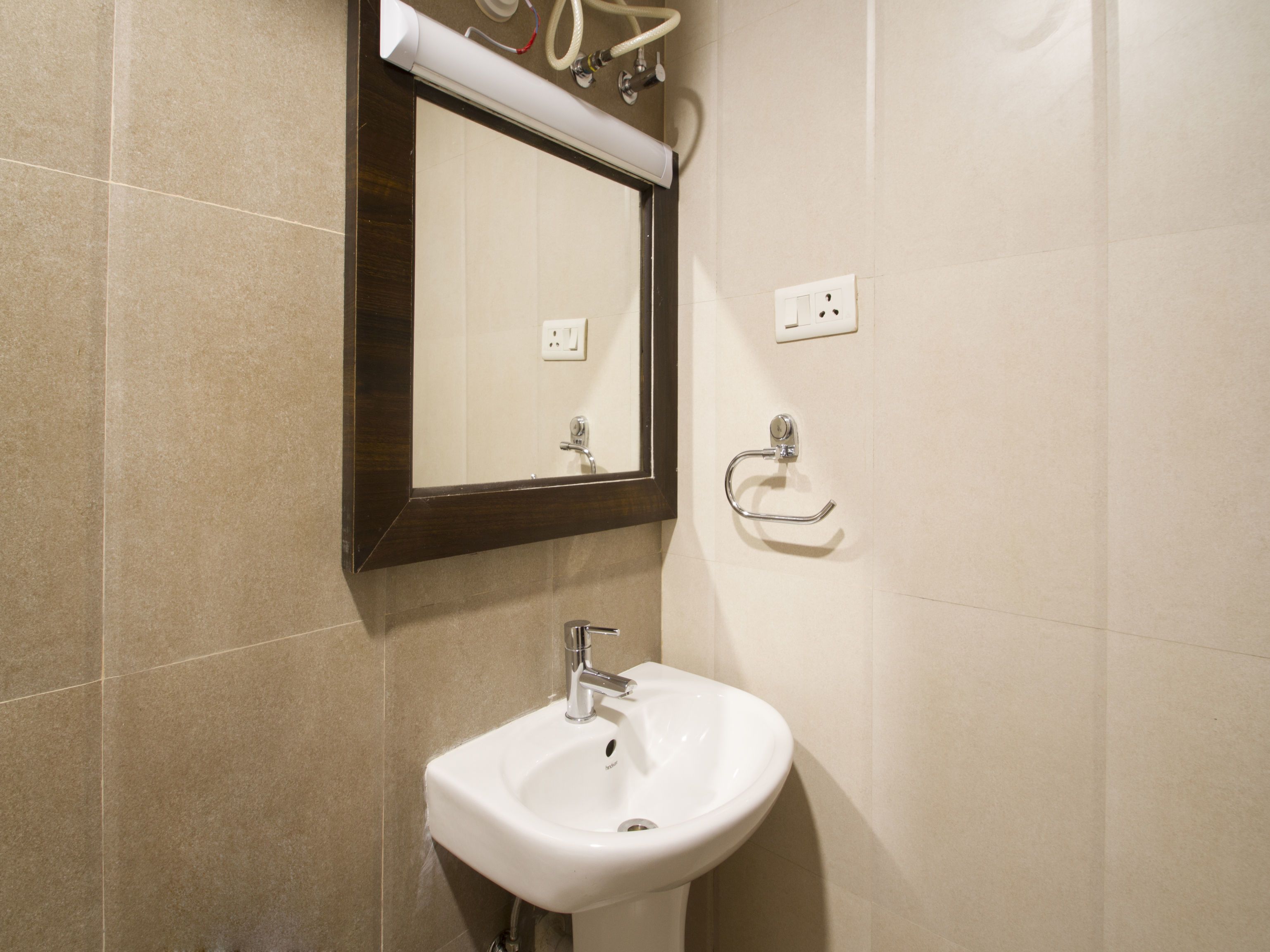 Een badkamer met een witte wasbak, een spiegel en een handdoekhouder.
