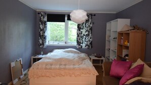 Een slaapkamer met een bed, een bureau, een kledingkast en een raam met gordijnen.