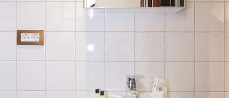A bathroom with a white sink, a mirror, and a towel hanging on the wall.