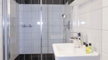 Ein modernes Badezimmer mit einer gläsernen Duschkabine, einem weißen Waschbecken und Fliesenboden.